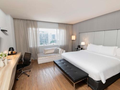 a hotel room with a large bed and a desk at Pullman Sao Paulo Vila Olimpia in Sao Paulo