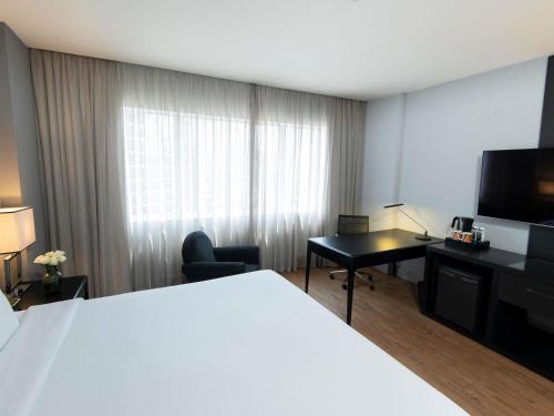 a hotel room with a bed and a desk and a television at Pullman Sao Paulo Vila Olimpia in Sao Paulo