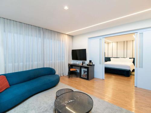 a living room with a blue couch and a bed at Pullman Sao Paulo Vila Olimpia in Sao Paulo