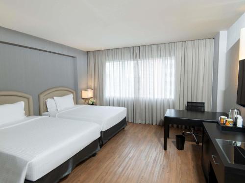 a hotel room with two beds and a desk at Pullman Sao Paulo Vila Olimpia in Sao Paulo