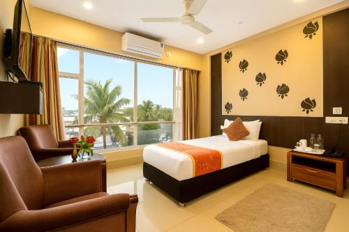 a bedroom with a bed and a chair and a window at Central Courtyard Boutique Hotel in Siliguri
