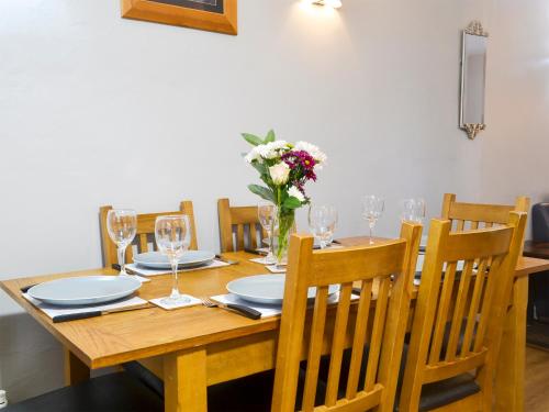 a dining room table with glasses and flowers on it at Fisherman's Cottage in Sheringham