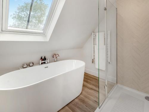 a white bathroom with a tub and a window at Swallow Barn in Danby