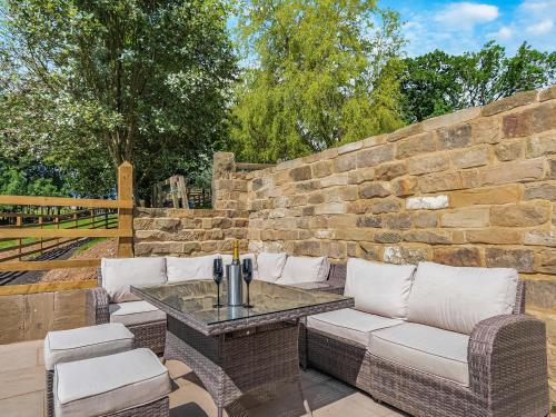 a patio with wicker furniture and a stone wall at Swallow Barn in Danby