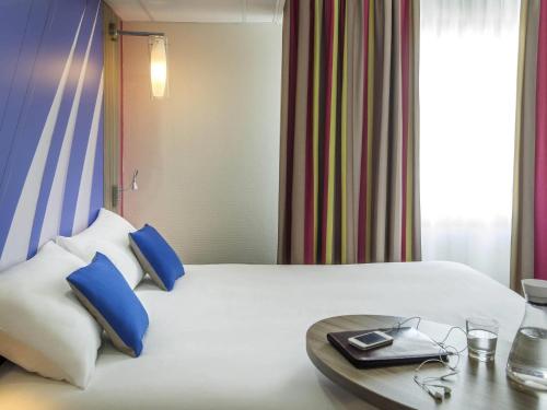 a hotel room with a white bed with blue pillows at ibis Styles St Gilles Croix de Vie centre-ville in Saint-Gilles-Croix-de-Vie