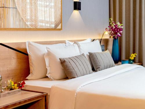 a bedroom with a bed with white sheets and pillows at Grand Mercure Sao Paulo Vila Olimpia in Sao Paulo