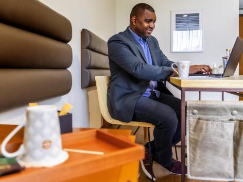 a man sitting at a table with a cup of coffee at Grand Mercure Sao Paulo Vila Olimpia in Sao Paulo