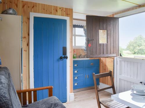 a kitchen with a blue door and a table at Skipton Shepherd's Hut - Dales View in Cononley