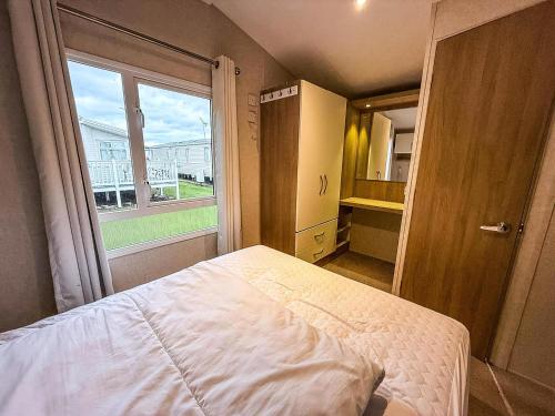 a bedroom with a bed and a large window at Lovely Dog Friendly Caravan For Hire At California Cliffs, Norfolk Ref 50027K in Great Yarmouth