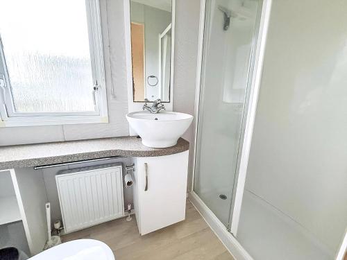 a bathroom with a sink and a toilet and a mirror at Lovely Dog Friendly Caravan For Hire At California Cliffs, Norfolk Ref 50027K in Great Yarmouth