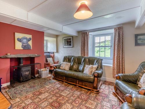 een woonkamer met lederen meubels en een open haard bij Haweswater Cottage in Bampton