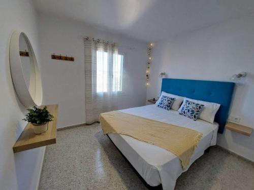 a bedroom with a large bed with a blue headboard at Garbí & Xaloc apartamentos in Cala Galdana