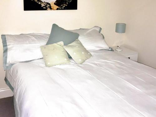 a white bed with four pillows on it at Hydan Creek Gardens in Wootton Bridge