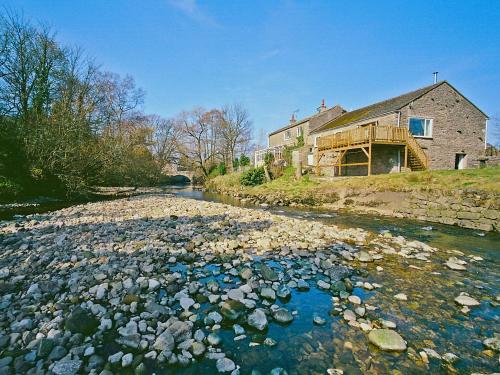 a river with rocks in front of a house at Lowmill in Kirkby Stephen