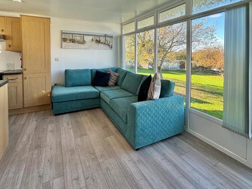 a living room with a blue couch in front of a window at Chalet 54 in Cromer
