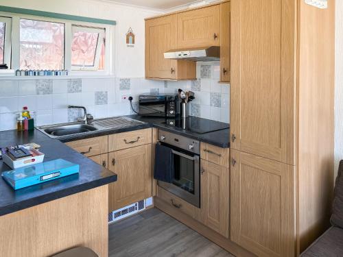 a small kitchen with wooden cabinets and a sink at Chalet 54 in Cromer