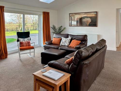 a living room with a leather couch and a chair at The Crofts in Winsford