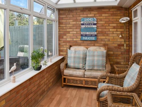 a porch with wicker chairs and a bench next to a window at Sea Escape in Heacham