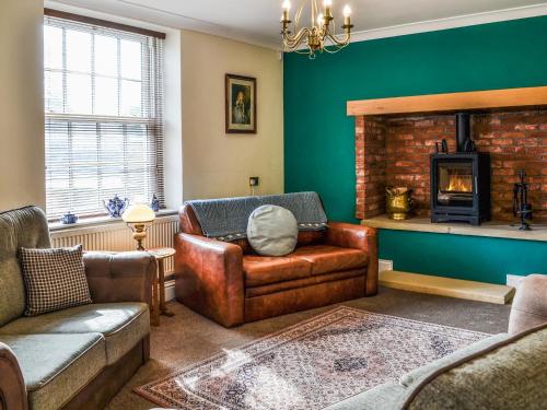 a living room with a leather chair and a fireplace at Beckbridge House in Pickering