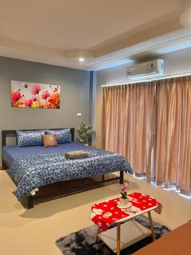 a bedroom with a bed and a table at Pluemjai mansion in Ban Kathu