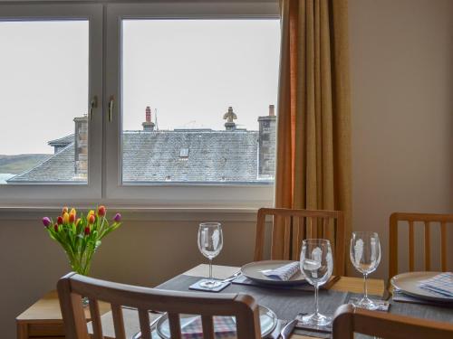 a dining room table with wine glasses and a window at Finlaggan Apartment in Oban