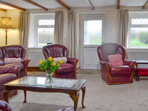 ein Wohnzimmer mit 3 Stühlen und einem Couchtisch in der Unterkunft Tirmynydd Farm Cottage in Dunvant