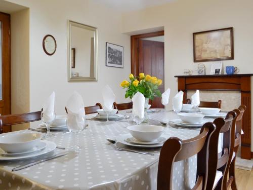einen Esstisch mit einem weißen Tischtuch und Stühlen in der Unterkunft Tirmynydd Farm Cottage in Dunvant