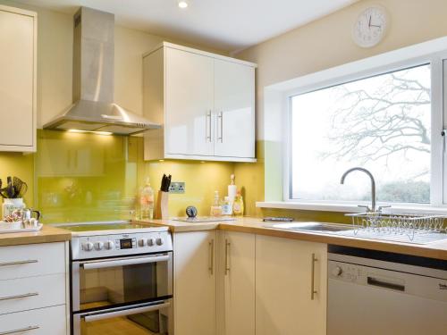 a kitchen with white cabinets and a sink and a window at Tirmynydd Farm Cottage in Dunvant