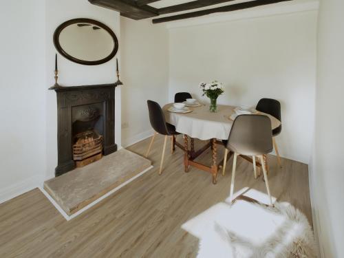 a dining room with a table and chairs and a fireplace at Lawns Cottage in Helmsley