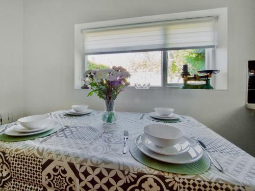 a table with plates and a vase of flowers on it at Lawns Cottage in Helmsley