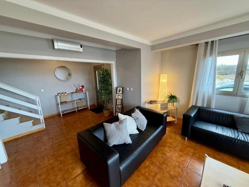 a living room with a black leather couch at Home in Paradise Costa de Lavos in Costa de Lavos