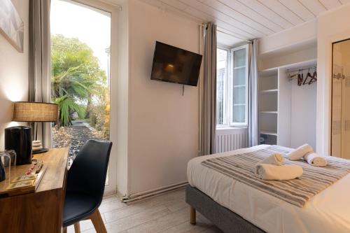 a bedroom with a bed and a desk and a window at Hôtel Le Square in Saint-Pierre-dʼOléron