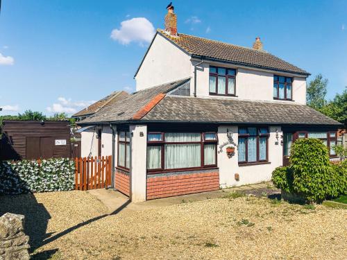 a white house with a fence in a yard at Black Pan Holiday Cottage in Shanklin