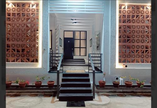 a hallway with stairs and a door with potted plants at Gorgeous villa near Eden beach in Puducherry