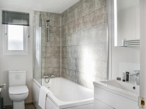 a bathroom with a tub and a toilet and a sink at Atmospheric in Patrington