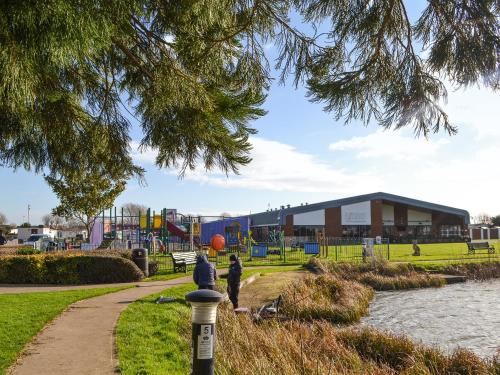 two people walking through a park with a playground at Atmospheric in Patrington