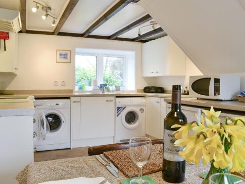 a kitchen with a table with a bottle of wine at Blairhosh Cottage in Balloch