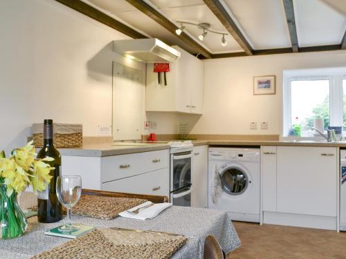 a kitchen with white cabinets and a table with a wine glass at Blairhosh Cottage in Balloch