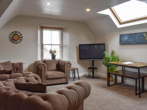 a living room with couches and a flat screen tv at West View Apartment in Bowness-on-Windermere