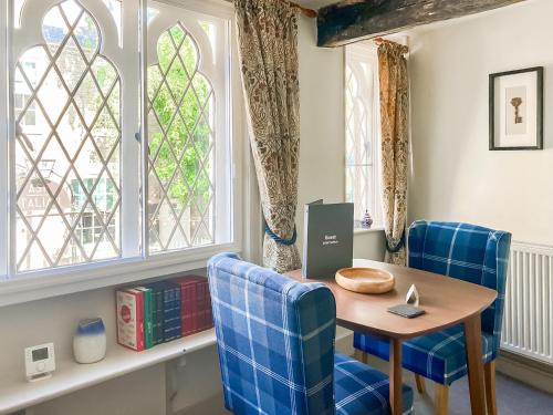 a dining room with blue chairs and a table and windows at The Knights Apartment, Eastbridge Hospital in Canterbury