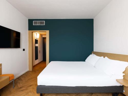 a bedroom with a white bed and a blue wall at Novotel Caserta Sud in Caserta