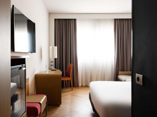 a hotel room with a bed and a desk at Novotel Caserta Sud in Caserta