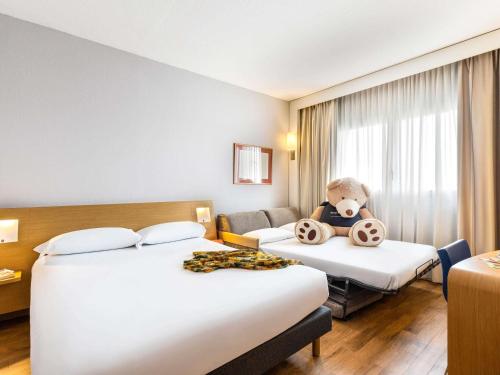 a hotel room with two beds with a teddy bear on them at Novotel Caserta Sud in Caserta