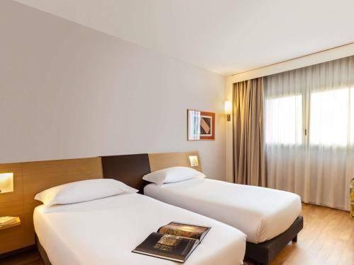 a hotel room with two beds and a book at Novotel Caserta Sud in Caserta