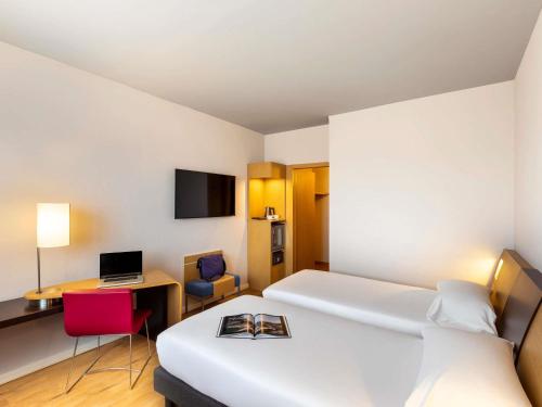 a hotel room with a bed and a desk with a laptop at Novotel Caserta Sud in Caserta