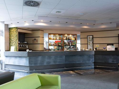 a lobby with a bar and a green couch at Novotel Caserta Sud in Caserta