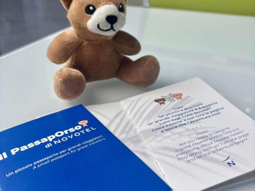 a teddy bear sitting next to a box and a pamphlet at Novotel Caserta Sud in Caserta