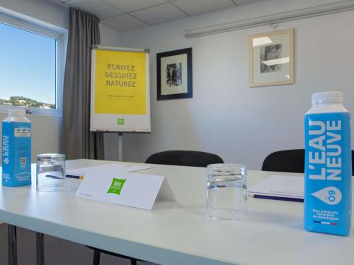 a table with a bottle of water and glasses on it at ibis Styles Cannes Le Cannet in Cannes