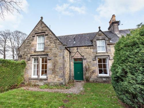an old stone house with a green door at Isla Bank Cottage in Keith