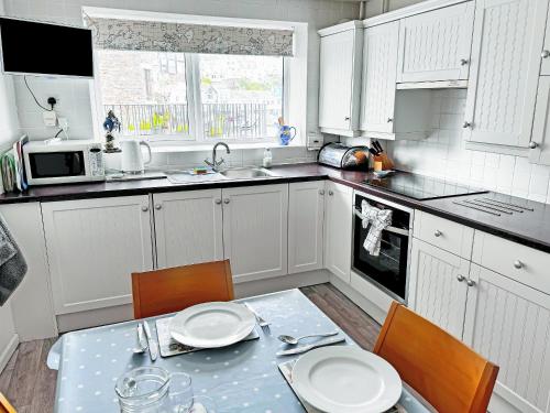 eine Küche mit weißen Schränken und einem Tisch und Stühlen in der Unterkunft Captain's Haven in Brixham